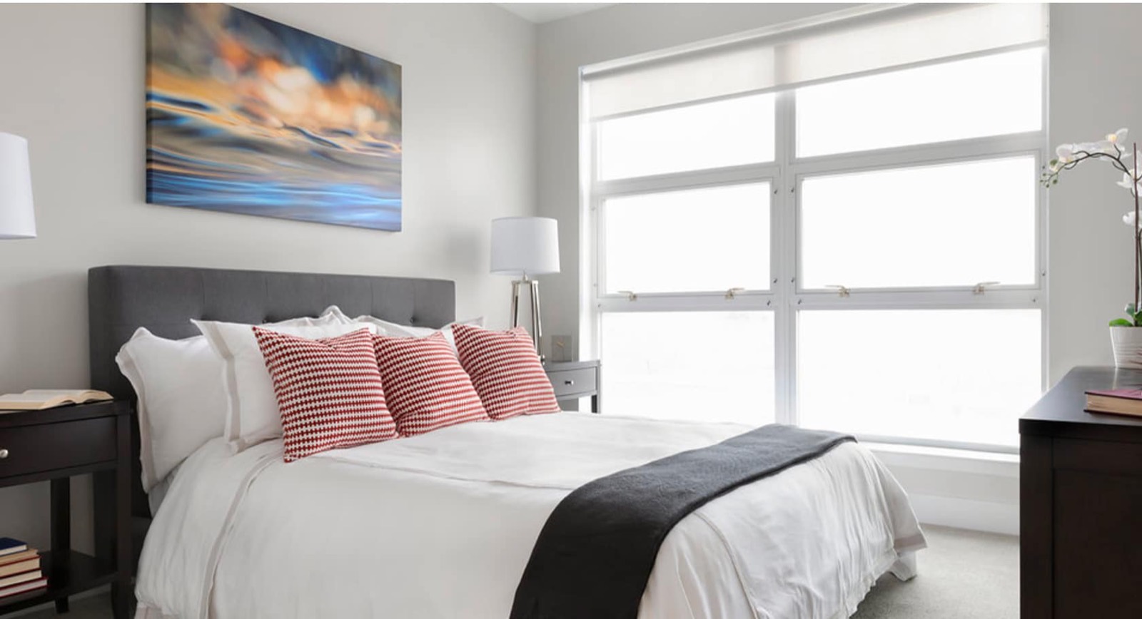 A bedroom with a queen bed and an extra-large window